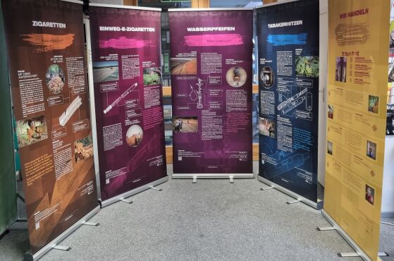 Ausstellung zu Lieferketten von Tabak- und Nikotinprodukten, fünf Rollups im Halbrund aufgestellt