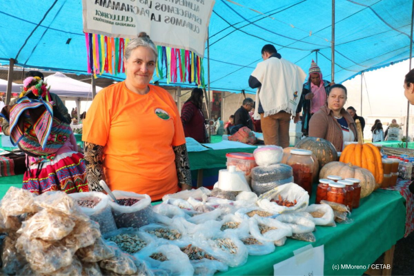 Frau bei einem traditionellen Saatgutmarkt, bietet verschiedenstes Saatgut an ihrem Stand an